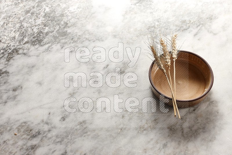 Wheat stalks on Beige Pottery Oven Bowl Plate on grey marble flooring, 45 degree angle