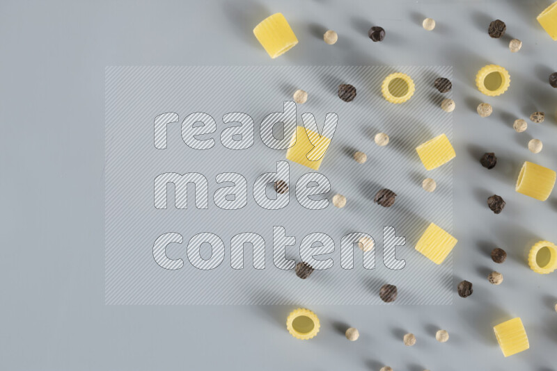 Raw pasta with different ingredients such as cherry tomatoes, garlic, onions, red chilis, black pepper, white pepper, bay laurel leaves, rosemary, cardamom and mushrooms on light blue background