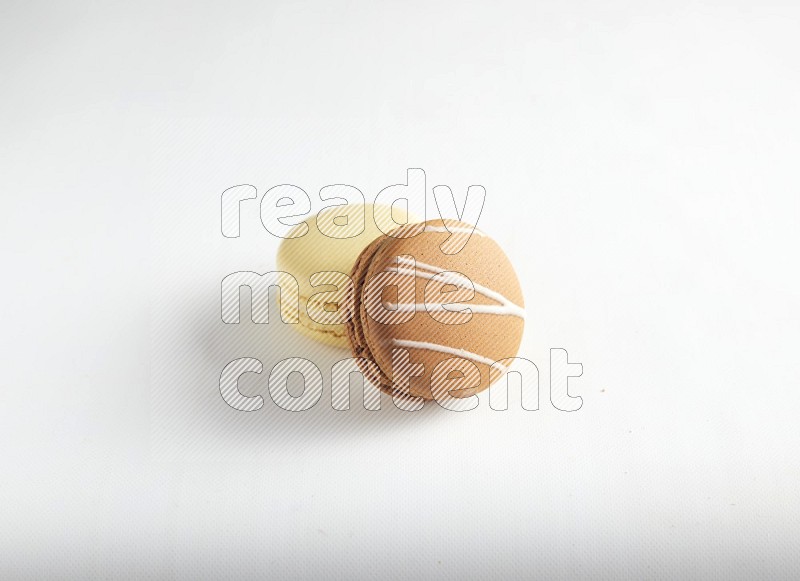 45º Shot of of two assorted Brown Irish Cream, and Yellow Vanilla macarons on white background