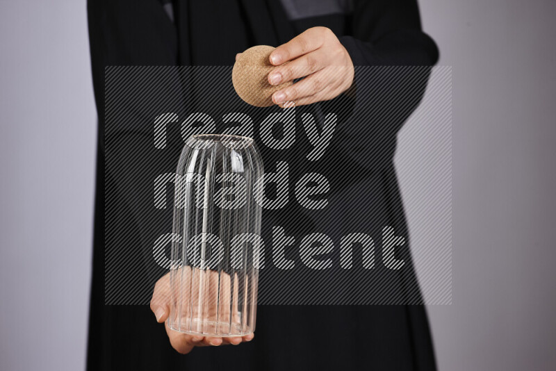 A woman in black abaya holding different glassware in different positions