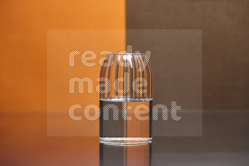 The image features a clear glassware filled with water, set against orange and brown background