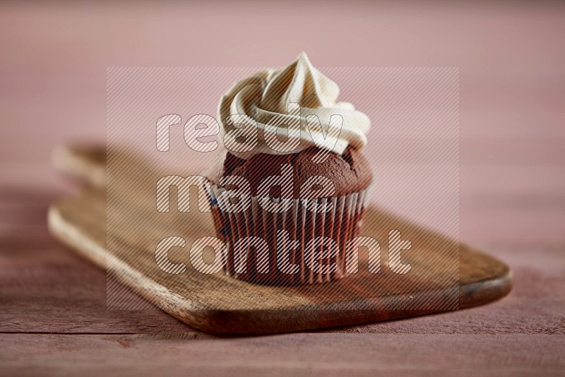 Chocolate cupcake topped with cream on a wooden board