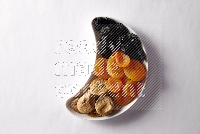 Mixed Dried fruits in a crescent pottery plate on white background