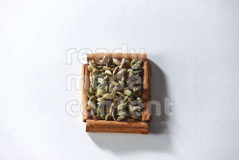 A single square of cinnamon sticks full of cardamom on white flooring