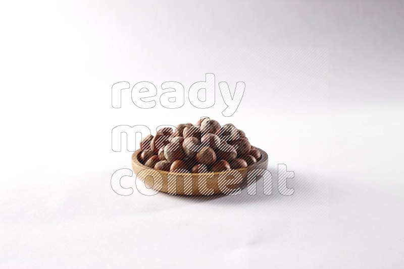 Hazelnuts in a wooden bowl on white background