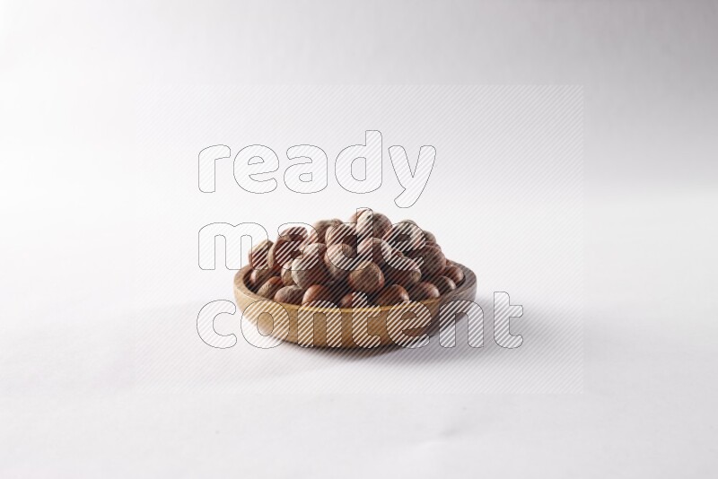 Hazelnuts in a wooden bowl on white background