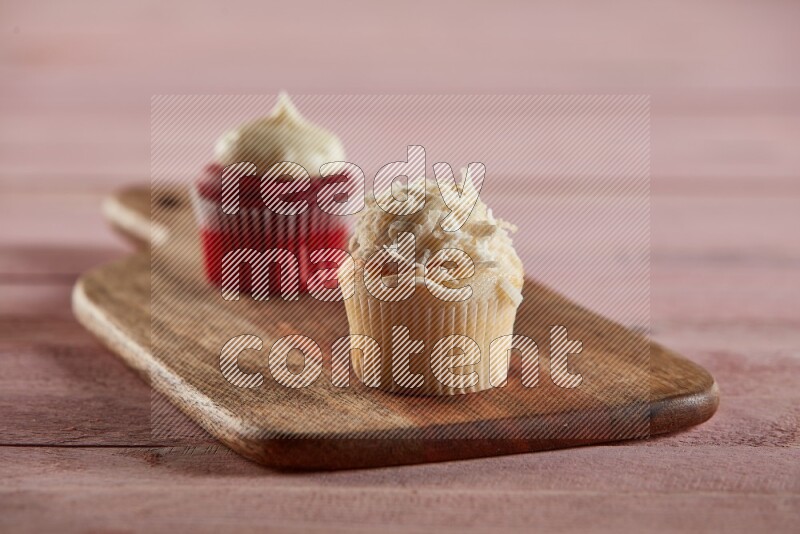 Vanilla mini cupcake topped with coconut on a wooden board