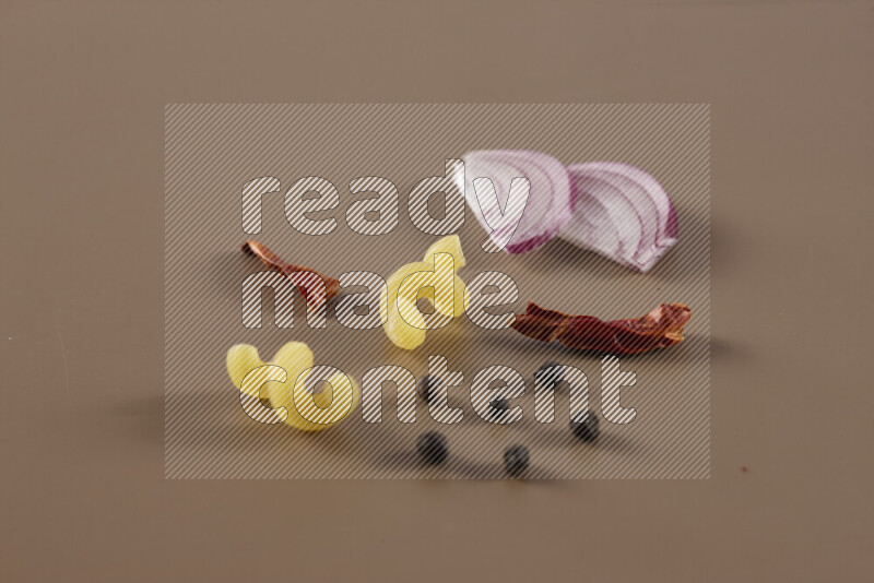 Raw pasta with different ingredients such as cherry tomatoes, garlic, onions, red chilis, black pepper, white pepper, bay laurel leaves, rosemary and cardamom on beige background