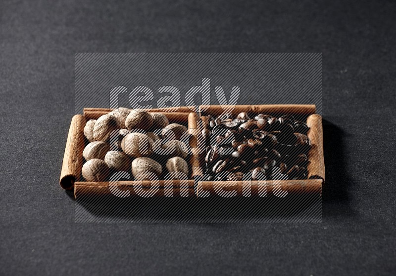 2 squares of cinnamon sticks full of coffee beans and nutmeg on black flooring