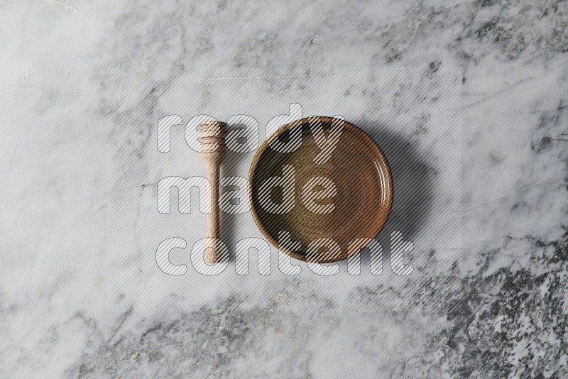 Multicolored Pottery Oven Plate with wooden honey handle on the side on grey marble flooring, Top view