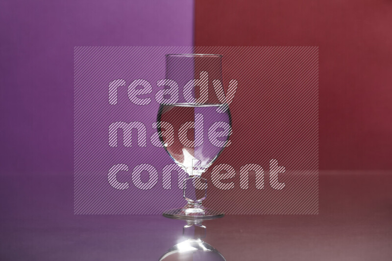 The image features a clear glassware filled with water, set against purple and dark red background