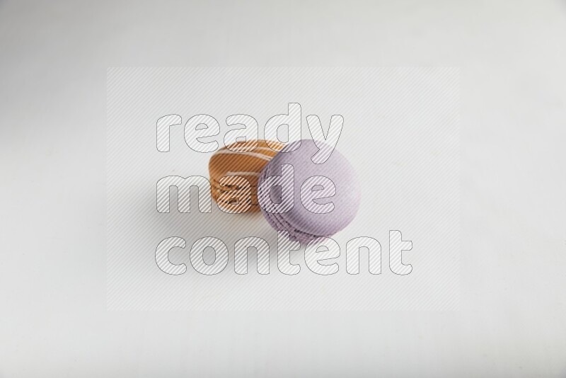 45º Shot of of two assorted Brown Irish Cream, and Purple Blueberry macarons on white background