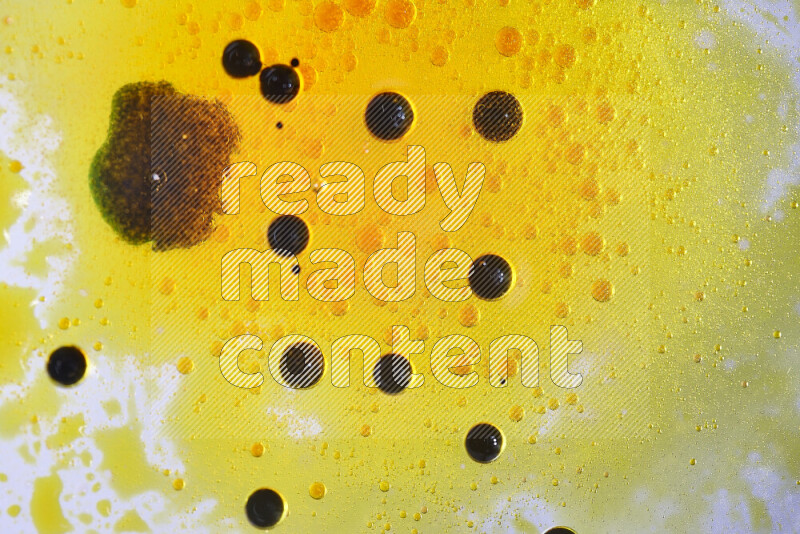 Close-ups of abstract yellow and black watercolor drops on oil Surface on white background