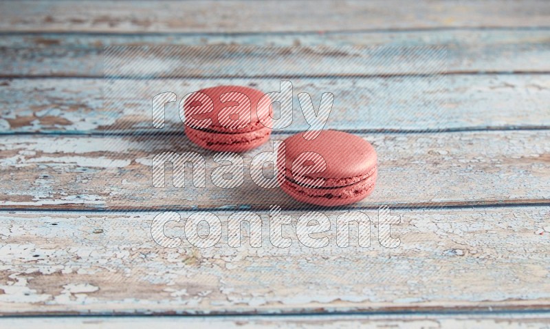 45º Shot of two Pink Raspberry macarons on light blue wooden background