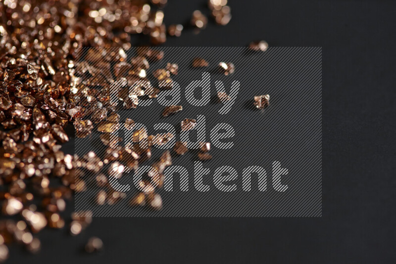 Bronze shimmering fragments of glass scattered on a black background