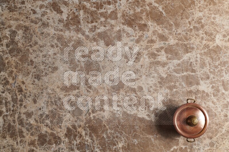 A small copper pot on beige marble background