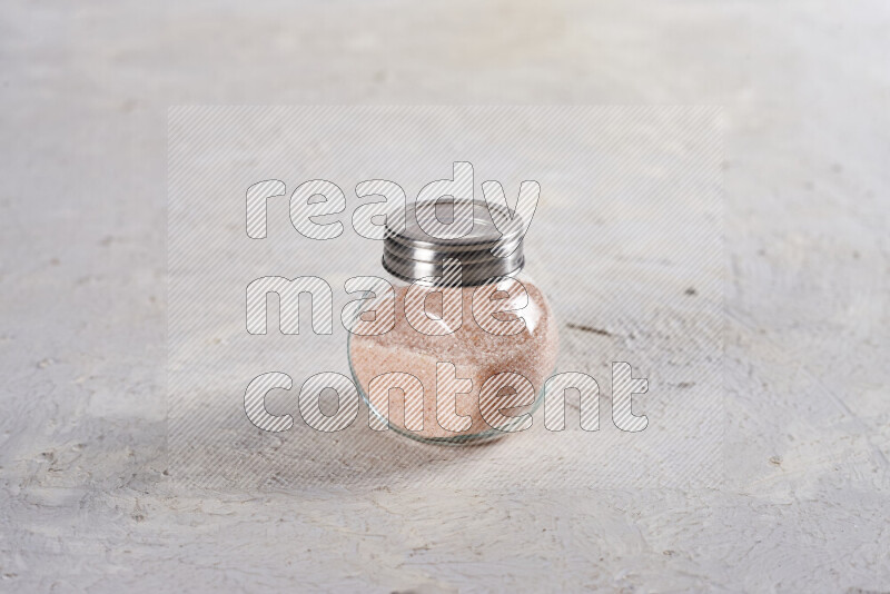 A glass jar full of fine himalayan salt on white background