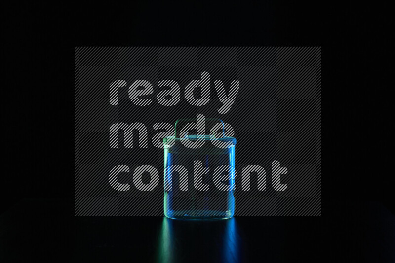 Glassware with rim light in blue and green against black background