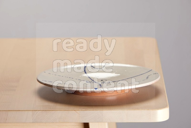 multi-colored pottery Plate on a wooden table edge