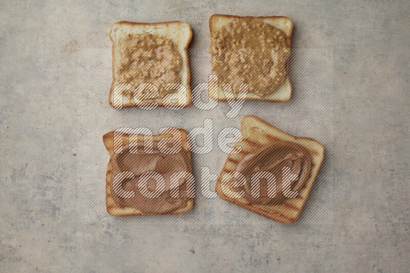 Creamy and crunchy peanut butter on a toasted white toast slices on a light blue textured background