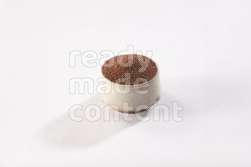 A beige pottery bowl full of garden cress seeds on a white flooring