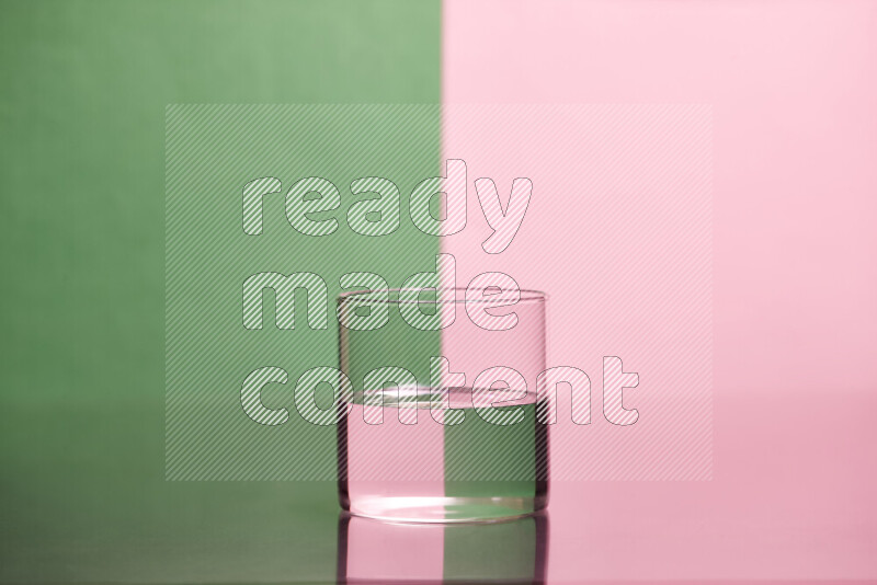 The image features a clear glassware filled with water, set against green and rose background