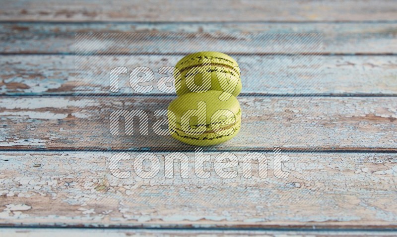 45º Shot of two Green Pistachio macarons on light blue wooden background