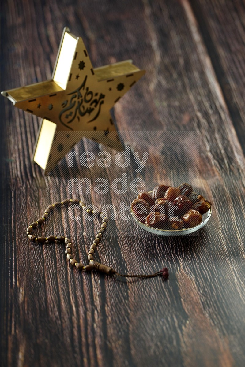 A star lantern with drinks, dates, nuts, prayer beads and quran on brown wooden background