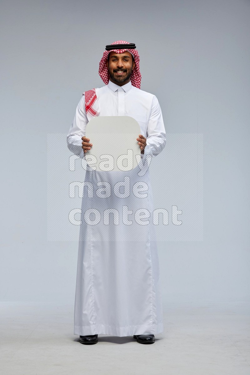 Saudi man Wearing Thob and shomag standing holding social media sign on Gray background