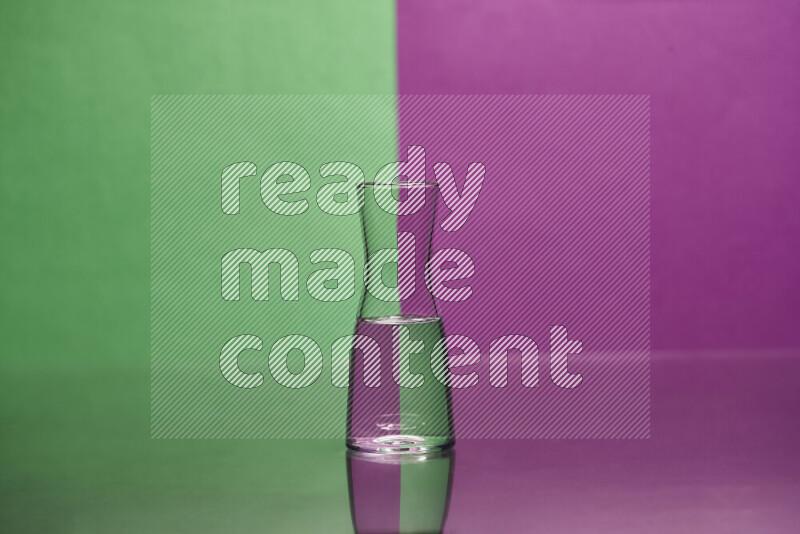 The image features a clear glassware filled with water, set against green and purple background