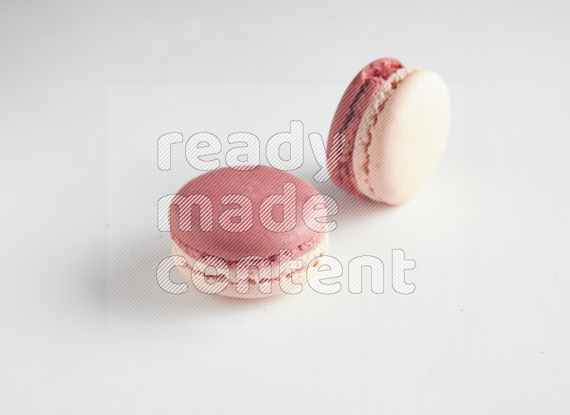 45º Shot of two Pink Litchi Raspberry macarons on white background