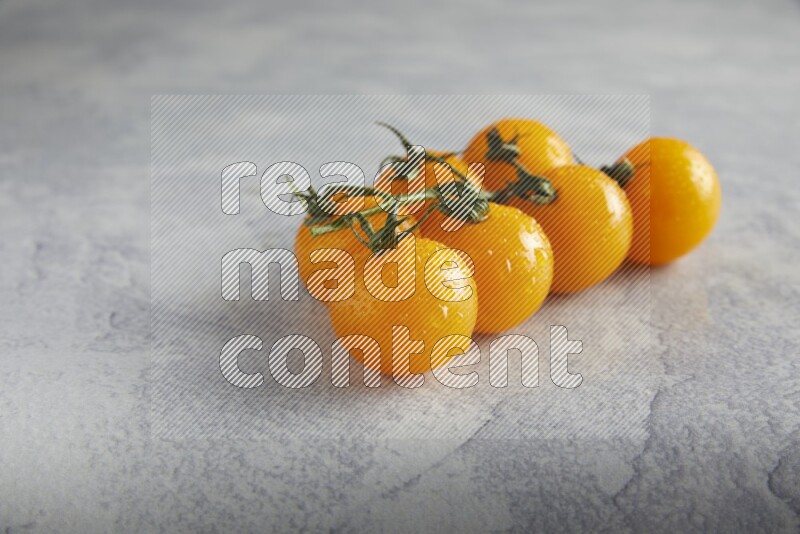 Yellow cherry tomato vein on a light grey textured background 45 degree