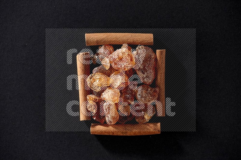 A single square of cinnamon sticks full of Arabic gum on black flooring