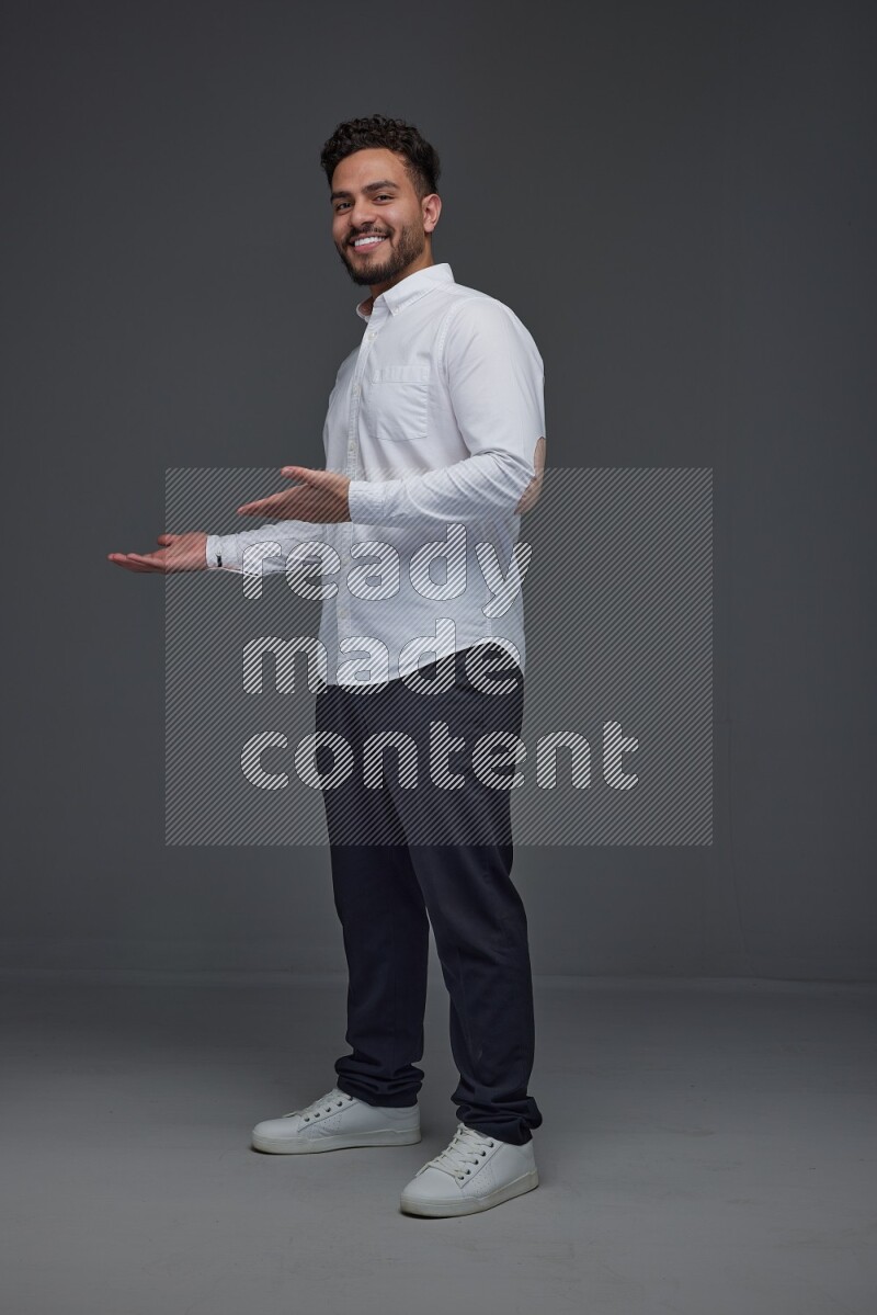 A man wearing smart casual standing and making multi hand gestures eye level on a gray background