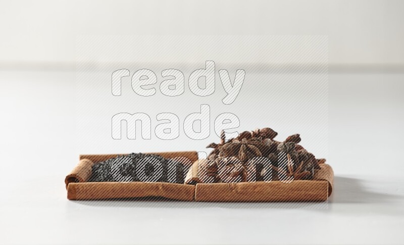 2 squares of cinnamon sticks full of black seeds and star anise on white flooring