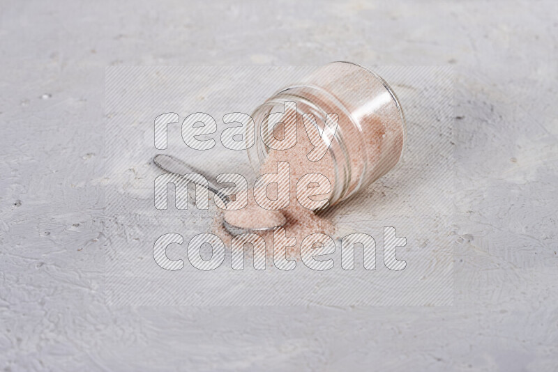 A glass jar full of fine himalayan salt on white background