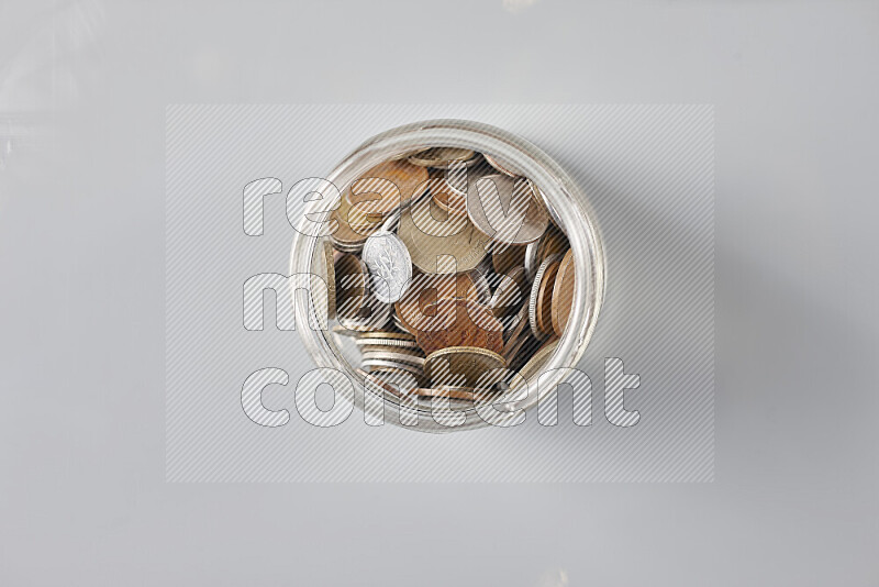 عملات معدنية قديمة عشوائية في وعاء زجاجي على خلفية رمادية