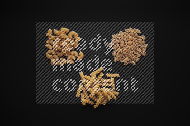 Different pasta types in bunches on black background