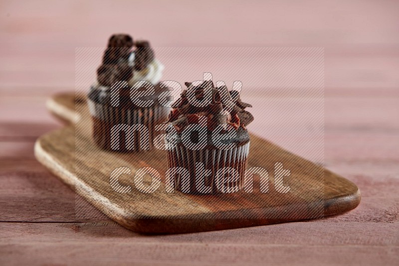 Chocolate mini cupcake topped with chocolate curls on a wooden board