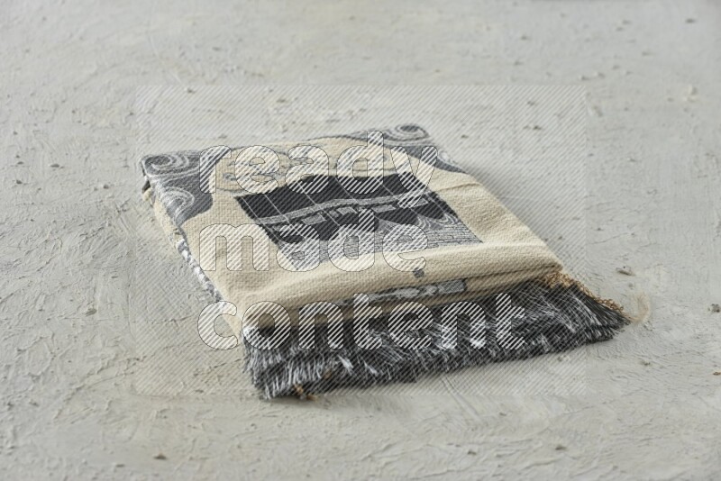 A folded prayer mat with different elements such as quran and prayer beads on white textured background