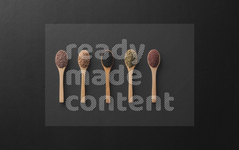 الفلفل الأسود وحبوب الخردل وحبة البركة وحب الرشاد والكمون و حبوب الكتان في معالق خشبية علي خلفية سوداء