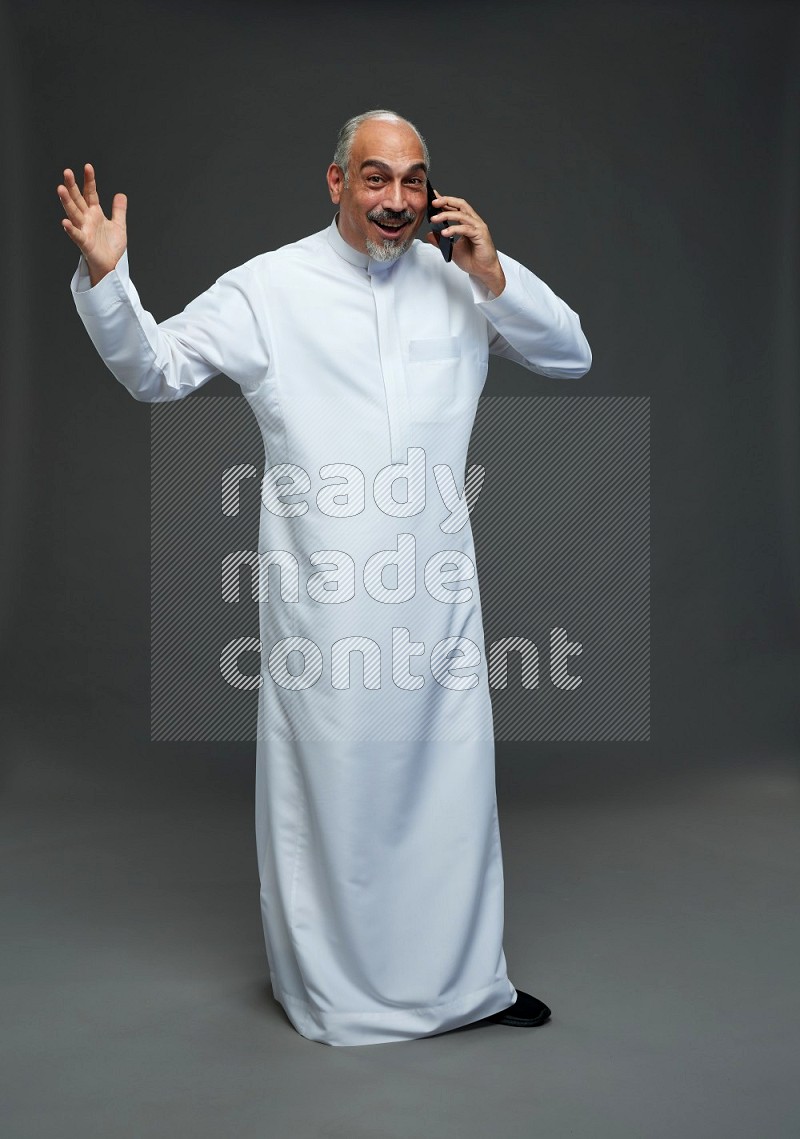 Saudi man without shomag Standing talking on phone on gray background
