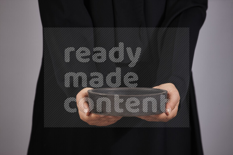 A woman in black abaya holding different pottery essentials in different positions