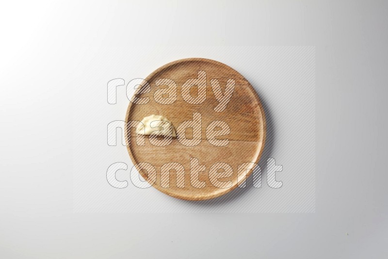 A single Sambosa on a wooden round plate on a white background