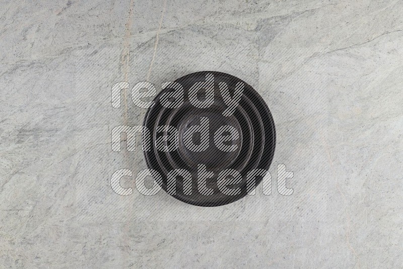 Top View Shot Of A Pottery Ripple Black Plate On Grey Marble Flooring