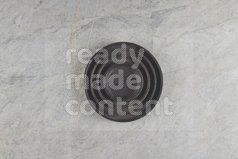 A pottery black ripple plate on grey marble background