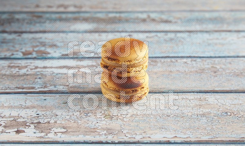 45º Shot of two Yellow Crème Brulée macarons on light blue wooden background