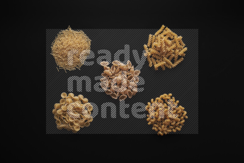 Different pasta types in bunches on black background