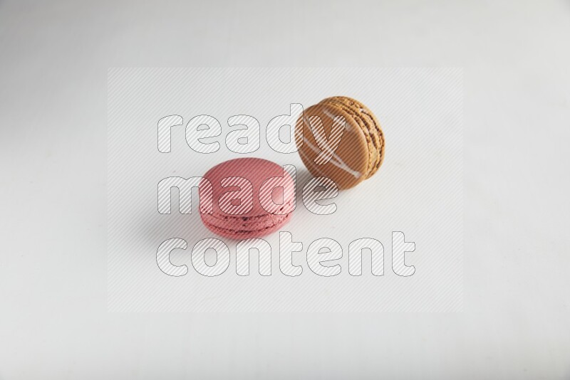 45º Shot of of two assorted Brown Irish Cream, and Pink Raspberry macarons on white background