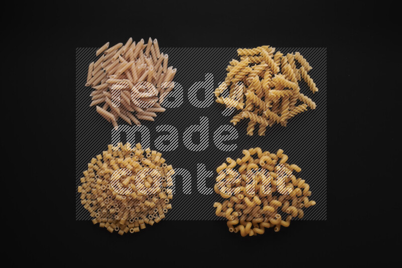 Different pasta types in bunches on black background